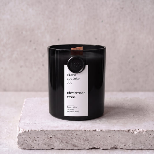 Christmas Tree candle hero — black glass vessel with wooden wick, fresh pine, cypress and vanilla musk — Flame Society Co.