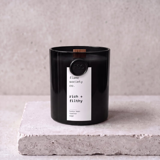 Rich + Filthy candle hero — black glass vessel with wooden wick, tonka bean, leather and sage — Flame Society Co.