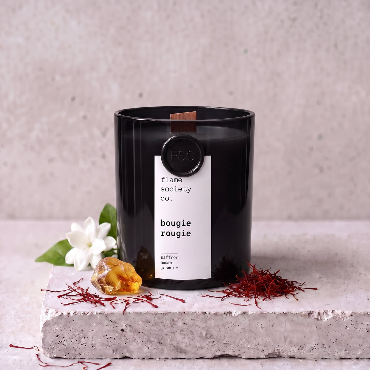 Bougie Rougie candle styled with saffron, amber and jasmine on concrete — Flame Society Co.