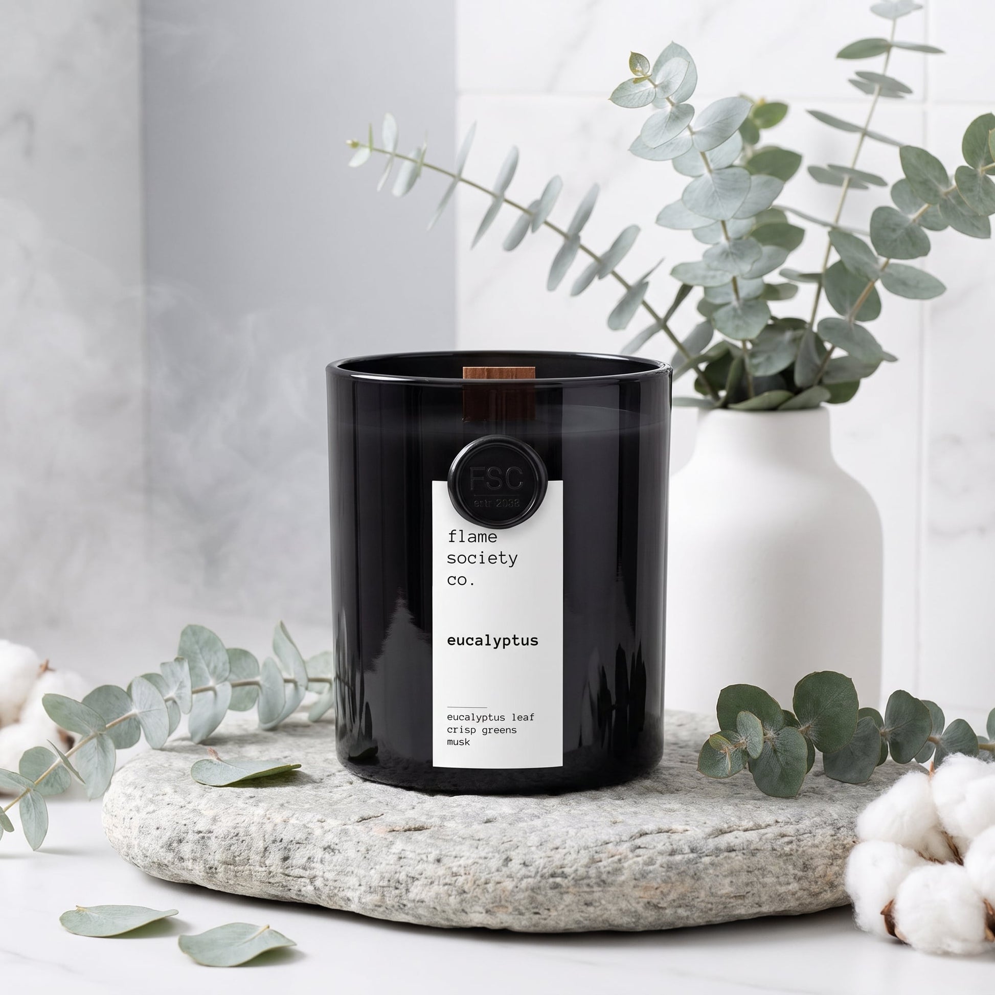 Flame Society Co. Eucalyptus candle in black glass vessel with fresh eucalyptus stems and cotton.