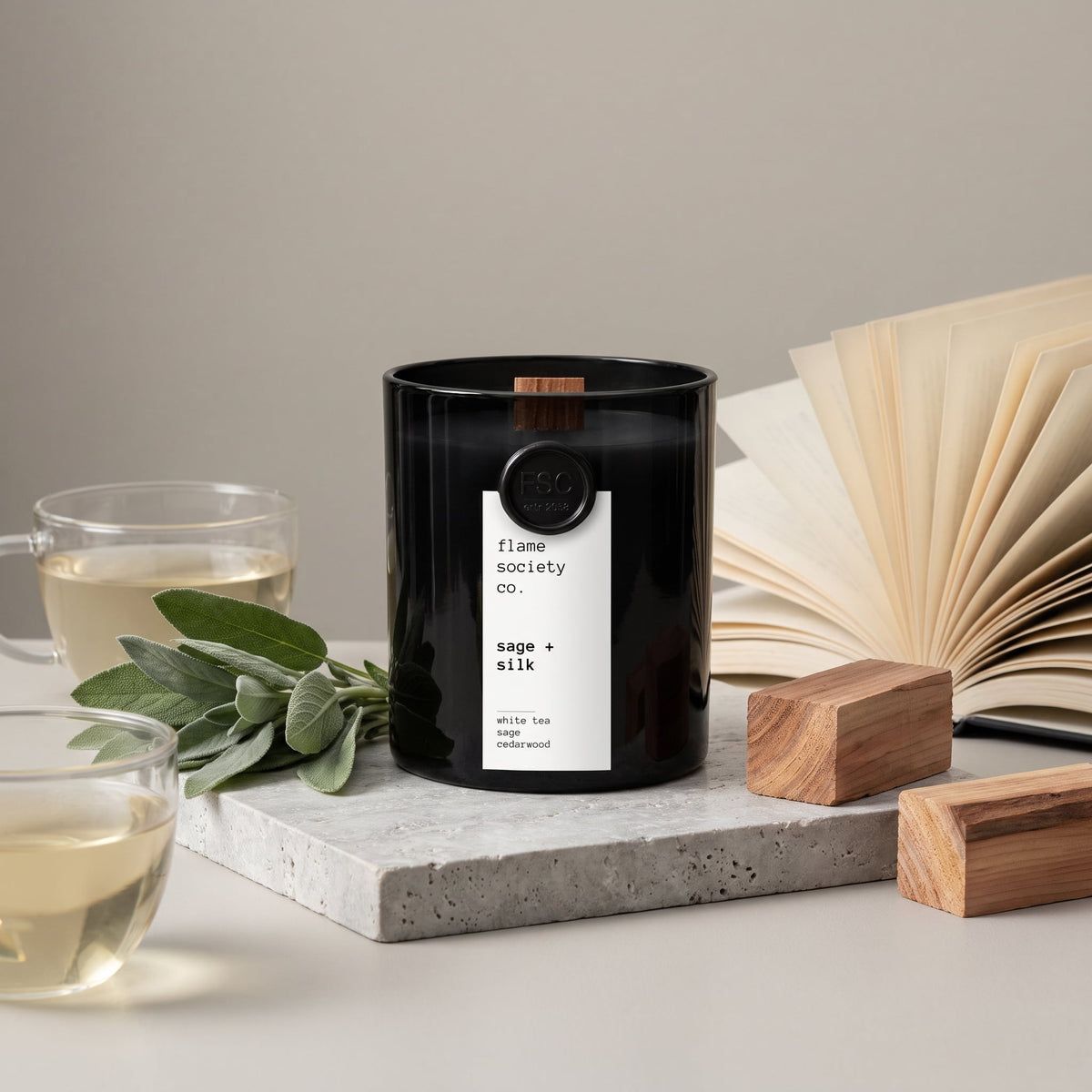 Flame Society Co. Sage + Silk candle in black glass vessel with fresh sage, white tea and cedarwood blocks.