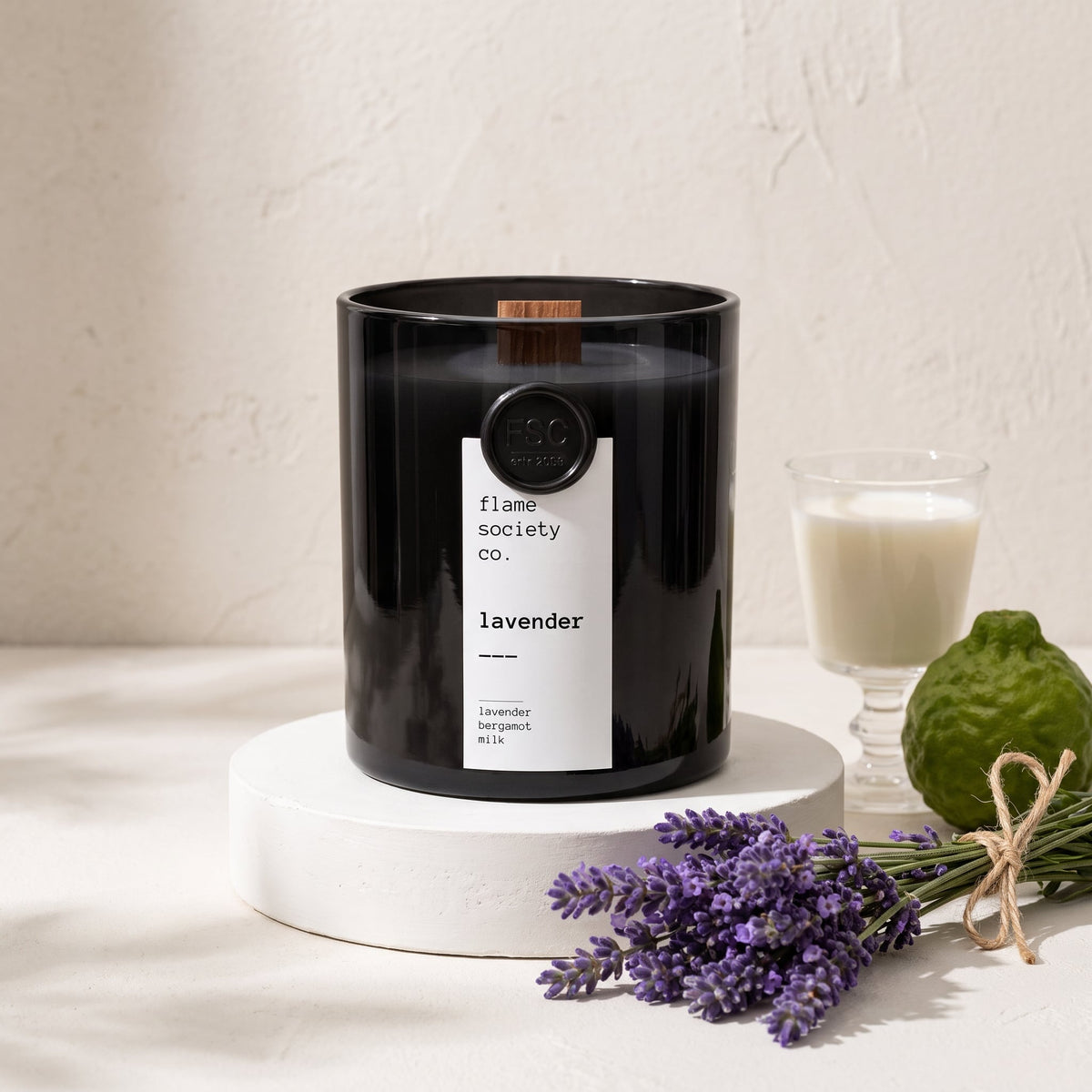 Flame Society Co. Lavender candle in black glass vessel with fresh lavender stems.