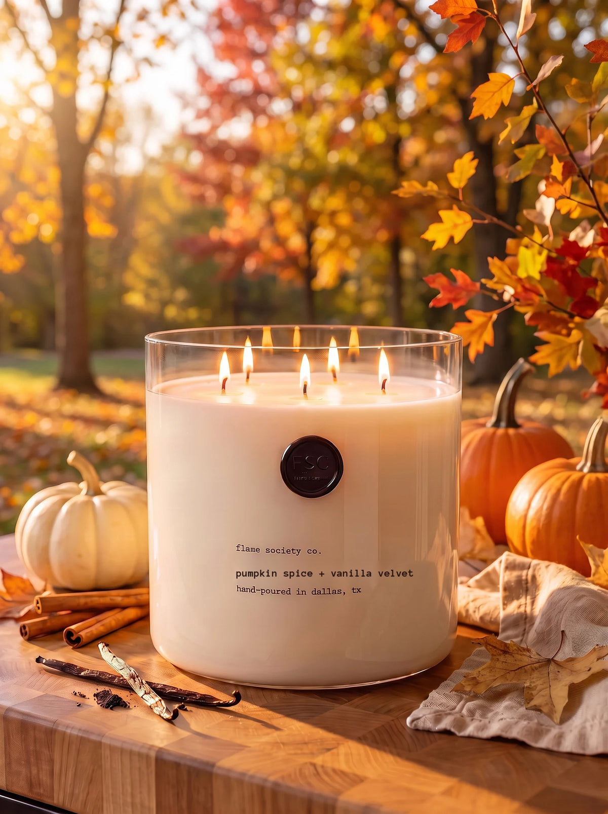 Pumpkin Spice + Vanilla Velvet XL 150oz statement candle in a clear glass vessel on an autumn table with pumpkins — Flame Society Co.