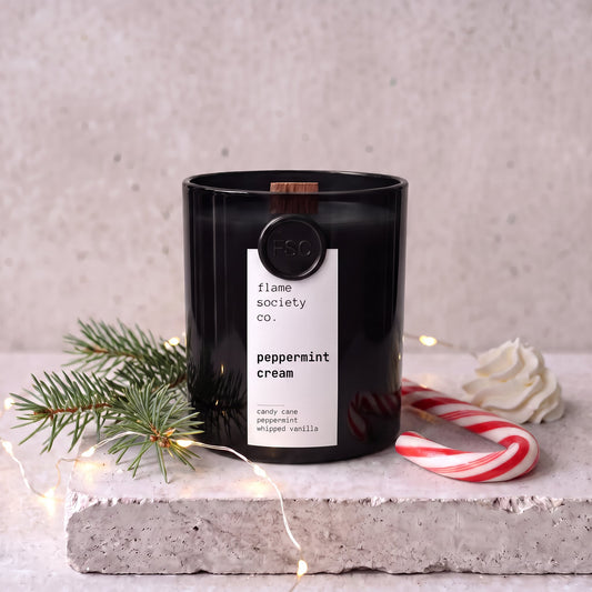 Peppermint Cream candle in black glass vessel styled with balsam fir, fairy lights, candy cane and whipped cream — Flame Society Co.