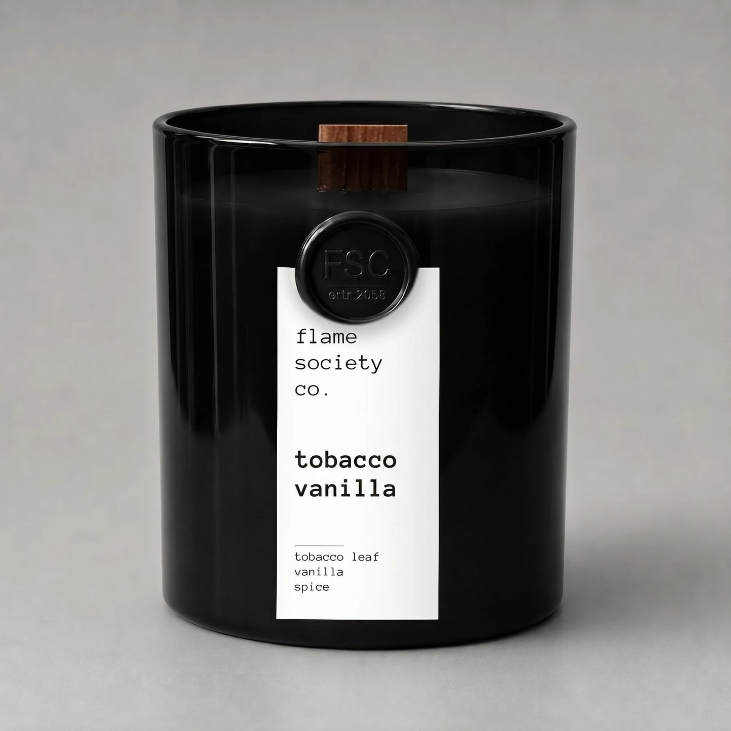 Black candle with a white label on a gray background