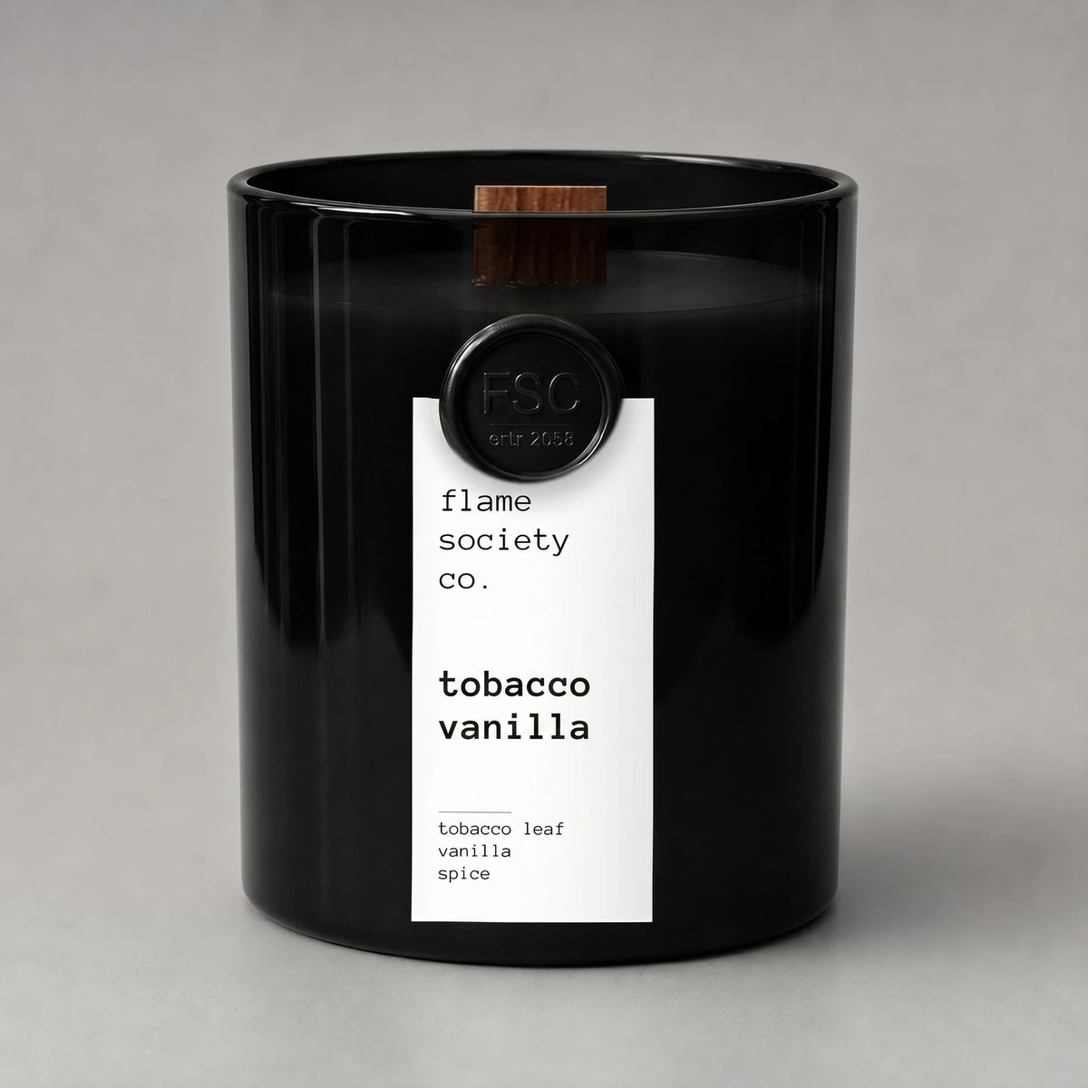 Black candle with a white label on a gray background