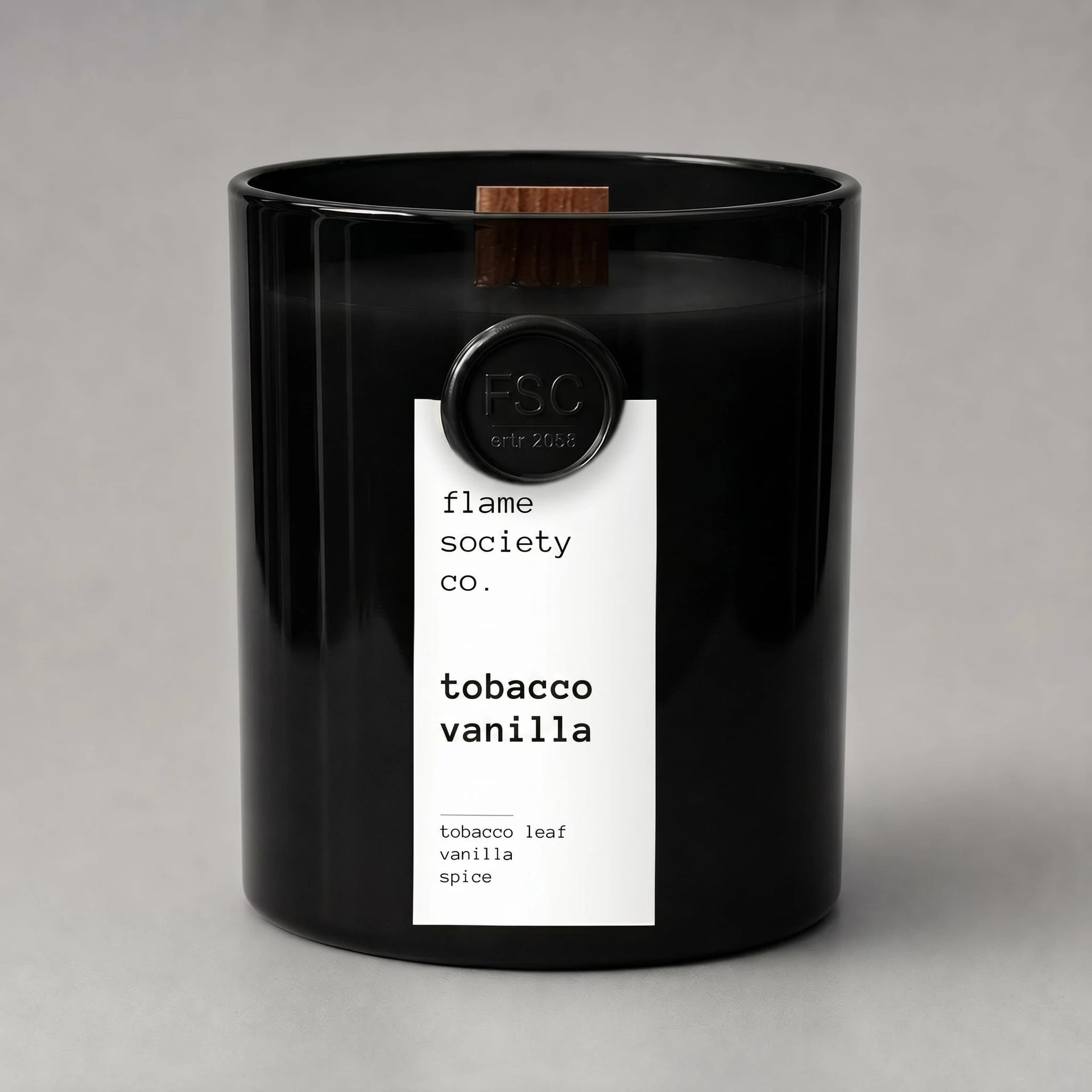 Black candle with a white label on a gray background