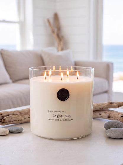 Light Hue XL 150oz statement candle in a clear glass vessel in a bright coastal living room — Flame Society Co.