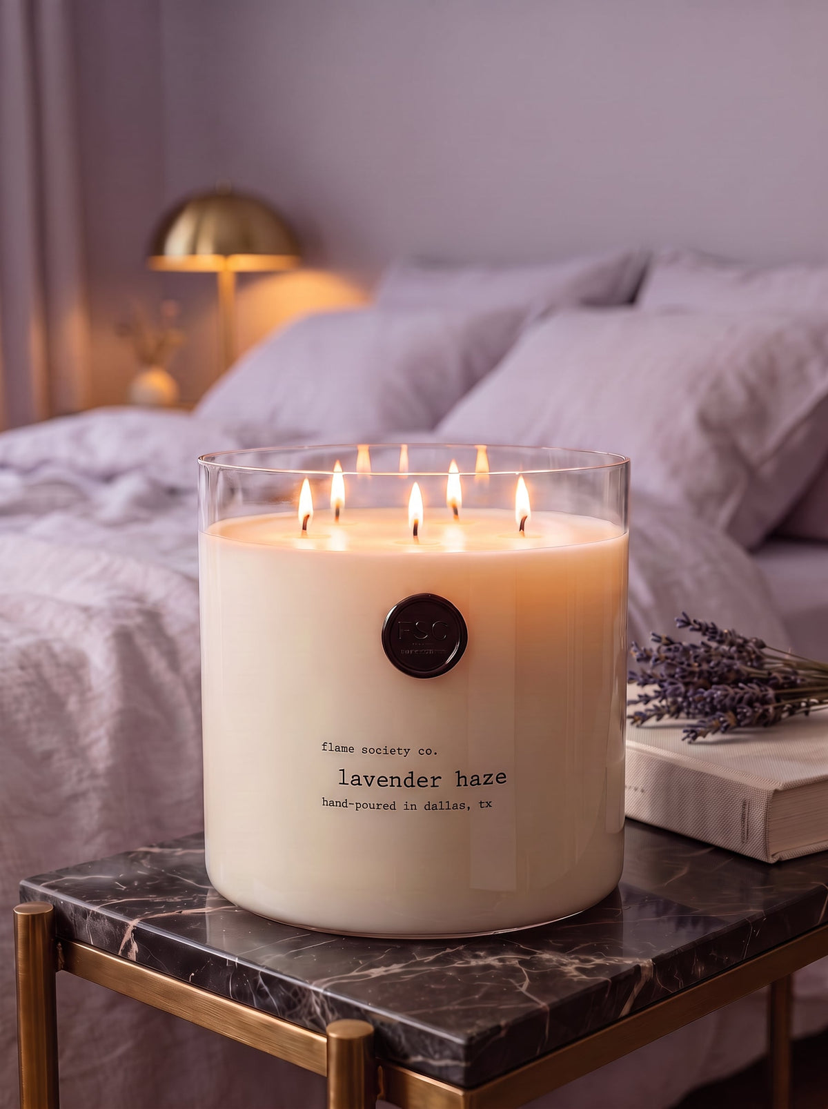 Lavender Haze XL 150oz statement candle in a clear glass vessel in a calm bedroom at dusk — Flame Society Co.