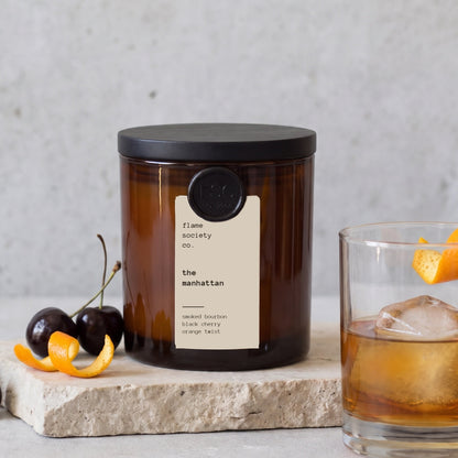 The Manhattan 10oz amber jar candle with a whiskey on the rocks, black cherries and orange peel on stone — flame society co.