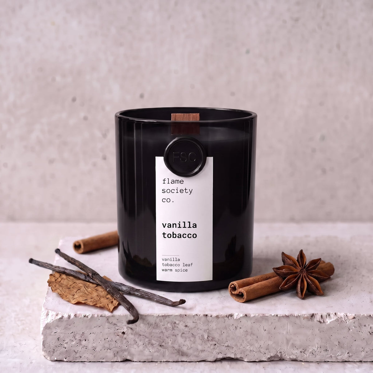 Vanilla Tobacco candle styled with vanilla, tobacco leaf and warm spice on concrete — Flame Society Co.