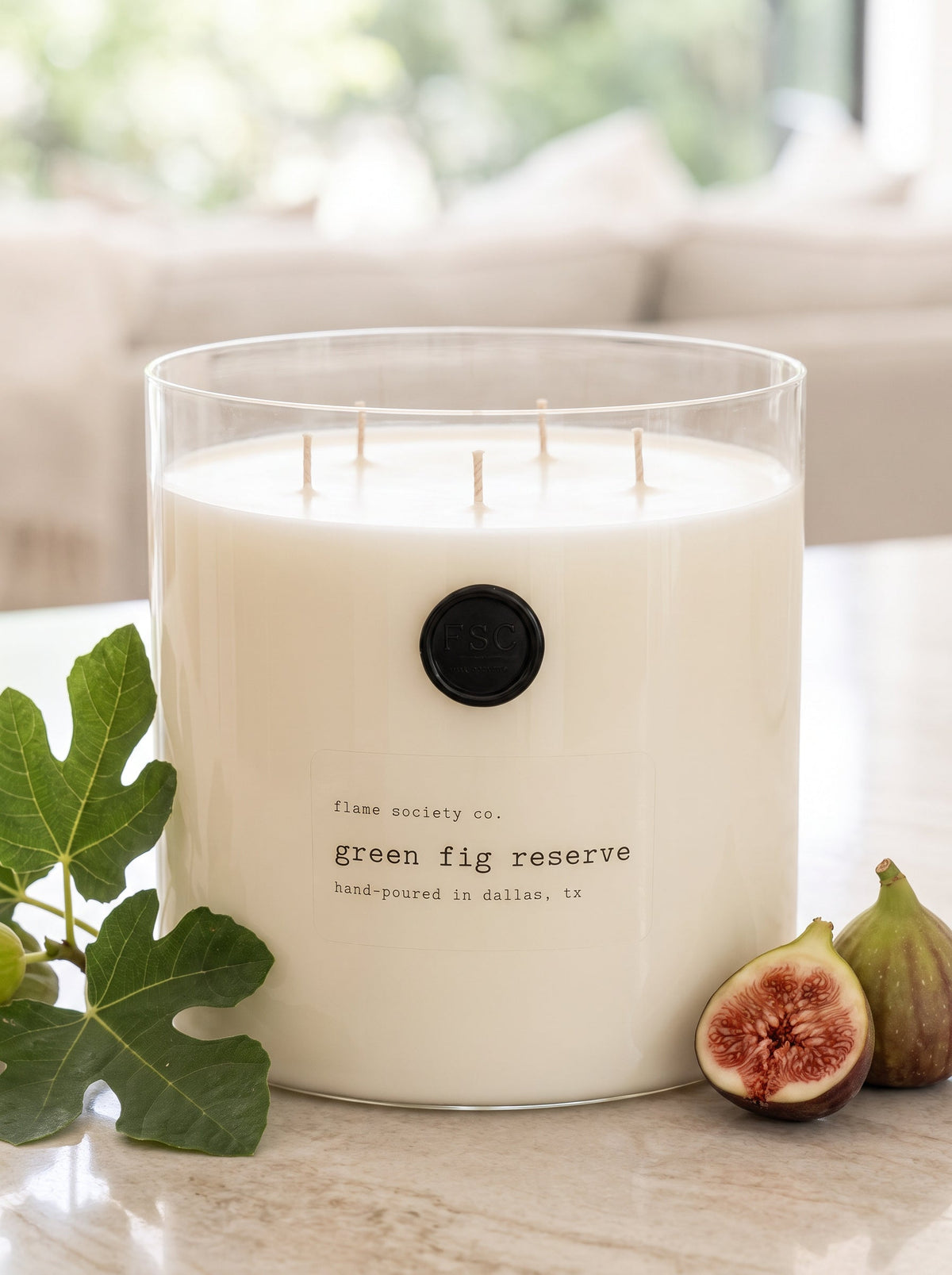 Green Fig Reserve XL 150oz statement candle in a clear glass vessel styled with fig leaves and halved figs — Flame Society Co.