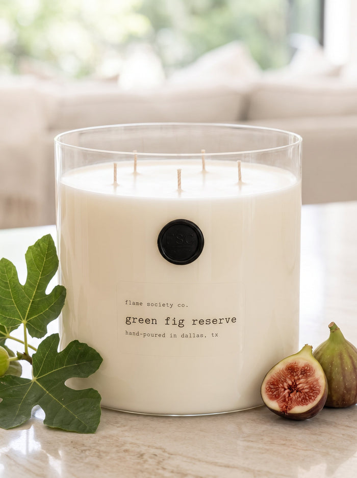 Green Fig Reserve XL 150oz statement candle in a clear glass vessel styled with fig leaves and halved figs — Flame Society Co.