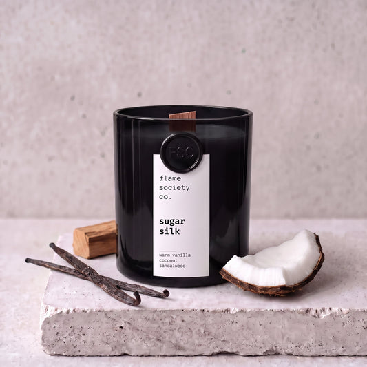 Sugar Silk candle styled with vanilla, coconut and sandalwood on concrete — Flame Society Co.