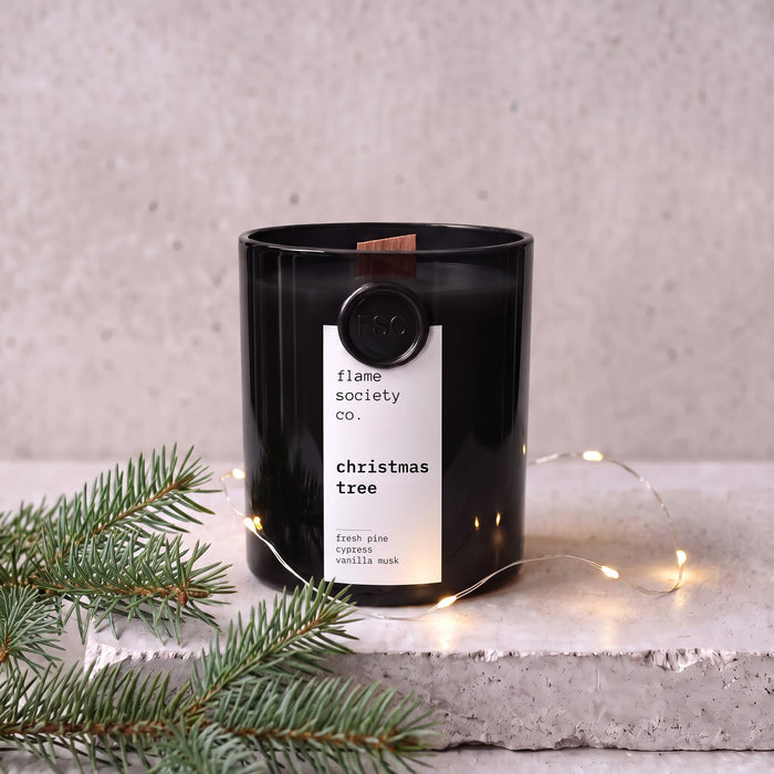 Christmas Tree candle in black glass vessel styled with balsam fir and warm fairy lights — Flame Society Co.