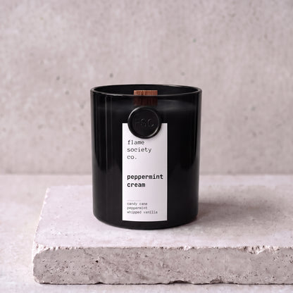 Peppermint Cream candle hero — black glass vessel with wooden wick, candy cane, peppermint and whipped vanilla — Flame Society Co.