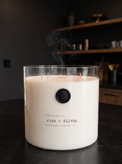 Rich & Filthy XL 150oz statement candle in a clear glass vessel on a dark countertop — Flame Society Co.