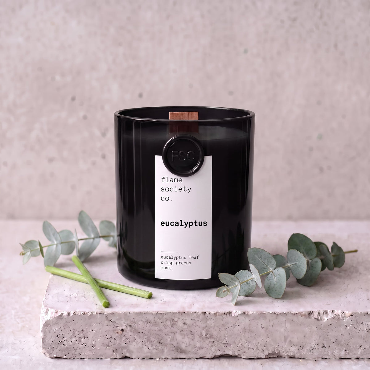 Eucalyptus candle styled with fresh eucalyptus and crisp greens on concrete — Flame Society Co.