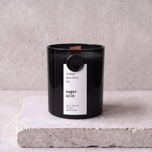 Sugar Silk candle hero — black glass vessel with wooden wick, warm vanilla, coconut and sandalwood — Flame Society Co.